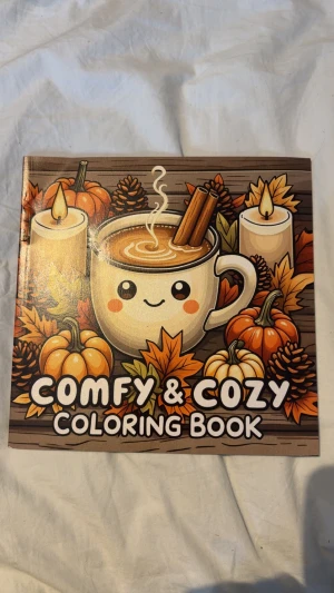 Comfy & Cozy Coloring Book - En mysig målarbok fylld med söta och höstiga motiv som varma drycker, pumpor, ljus och korgar. Perfekt för dig som vill koppla av och släppa loss kreativiteten med färgpennor. Passar både ungdomar och unga vuxna som älskar att färglägga och skapa en chill vibe.