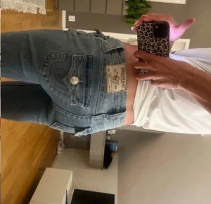 True religion jeanss 🩵 - Säljer ett par ljusblå jeans från True Religion med ikonisk bakficka och silverfärgad knappdetalj. Modellen har låg midja och bootcut-ben, klassisk jeanslook med snygga sömmar och patch på bakfickan. Perfekt för dig som gillar street och retrovibe.