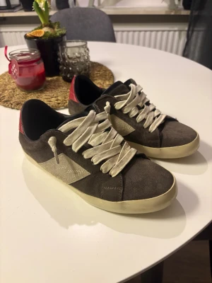 Zadig & Voltaire sneakers  - Snygga sneakers från Zadig & Voltaire i brun mocka med vita detaljer och röd häl. Skorna har vit snörning, platt sula och rund tå. Perfekta för dig som gillar en stilren men ändå cool look. Kommer med originalkartong och dustbag | skorna är i fint skick med inga större defekter | Nypris 2800, mitt pris 1599
