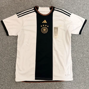 Tysklands fotbollströja Adidas S - Säljer Tysklands fotbollströja från Adidas med lappen kvar, i storlek S men passar även som M, 71cm på längden och 54 på bredden. Hör av dig vid frågor eller behov av fler bilder.