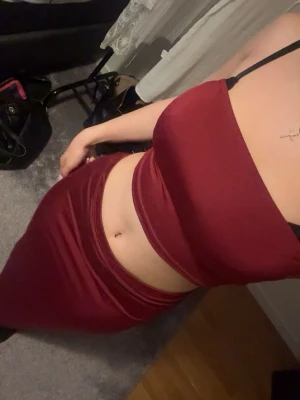 Vinröd croppad linnetopp och kjol set  - Säljer en vinröd croppad linnetopp utan axelband och lång maxi kjol.  De har en tight passform och är tillverkad i ett glansigt, mjukt material som ger en lyxig känsla. 