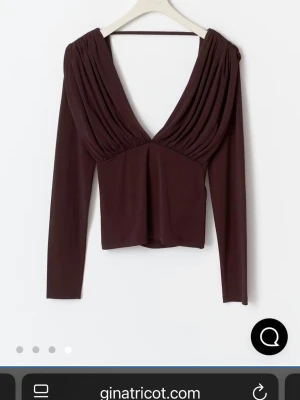 Vinröd/brun omlottopp med öppen rygg - Säljer en vinröd omlottopp från Gina Tricot med djup v-ringning och snygg drapering både fram och bak. Toppen har långa ärmar och en öppen rygg med en tunn rem upptill. Tillverkad i mjukt, stretchigt material som sitter skönt på kroppen. ANVÄND 1 Gång, säljer då den sitter lite för stort på mig 