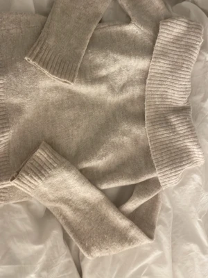 Beige polotröja från Gina Tricot - Mysig beige polotröja från Gina Tricot med bred ribbad krage och muddar. Tröjan är stickad och har lång ärm, perfekt för kyliga dagar. Enkel att styla med jeans eller kjol för en clean och chill look.🧥