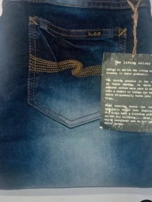 Nudie Jeans Slim Jim blå jeans - Säljer ett par Nudie Jeans Slim Jim i blå tvätt med snygg slitning och klassiska kontrastsömmar. Jeansen har rak passform, fem fickor och är tillverkade i bomull. Perfekta för dig som gillar en clean men ändå avslappnad look.