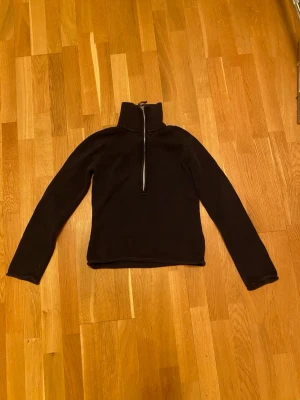 Svart stickad tröja med half zip Boomerang - Mörk stickad tröja från Boomerang i storlek M. Tröjan har hög krage och en snygg half zip-dragkedja med läderdetalj. Långärmad och i klassisk svart färg, perfekt för kyliga dagar. Enkel och stilren design som funkar till det mesta. Har krymp i tvätten men går att strecka ut igen 