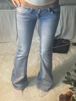 Ljusblå jeans Gina 14+ - Säljer ett par ljusblå bootcut jeans med låg midja och slitningar på framsidan. Jeansen har snygga broderade bakfickor med lock och knappdetaljer. Klassisk femficksmodell i mjukt denimtyg som sitter skönt på höften. Jeansen är helt nya och slutsålda på hemsidan, storlek Xs regular!! OM NI SKA KÖPA KÖP FRÅN MIN VINTED 💞 Heter : Aliceenglin