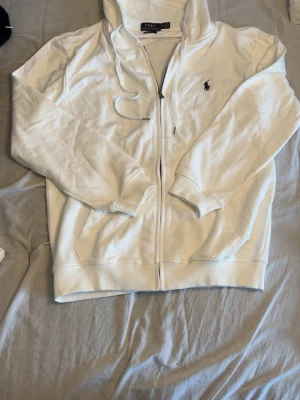 Ralph Lauren zip  - En vit Ralph Lauren Zip med svart logga. Köpt från Facebook marketplace som ny och bara test använd. Köpte den men passade inte jätte bra. Storlek M. Finns ångerrätt så går att köpa och skicka tillbaka om den inte passar eller något annat beskymmer så länge det köps via appen. Vid mer frågor eller funderingar hör gärna av er till mig.