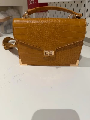 handväska - Snygg handväska i kamouflagefärg Mellanstor väska tillverkad av konstläder  Väskan är praktisk och rymlig, passar perfekt för vardagsbruk. I gott skick och bekväm att bära.