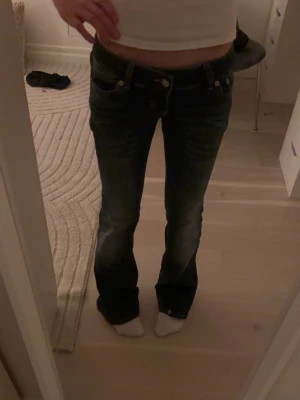 Lågmidjade Mörkblå bootcut jeans - Säljer ett par mörkblå jeans med bootcut passform. Jeansen har klassisk femficksdesign och är tillverkade i ett slitstarkt denimtyg. Snygg tvätt med lätt slitning vid benslut och sömmar. Perfekta för dig som gillar en retroinspirerad look. Från början köpta för 399. Skriv om ni vill ha några mått.