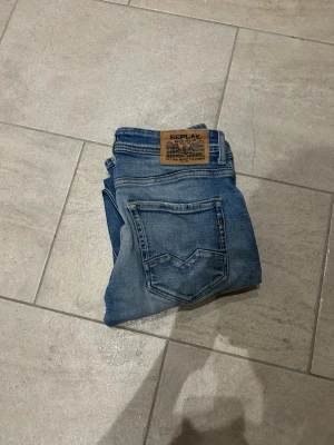Replay Rocco jeans i ljusblå denim - Säljer ett par Replay Rocco jeans i ljusblå tvätt med klassiska fem fickor och snygga slitningar. Jeansen har raka ben och normal passform, med Replay-lapp bak i midjan. Perfekta för dig som gillar en avslappnad men stilren look. 30/32