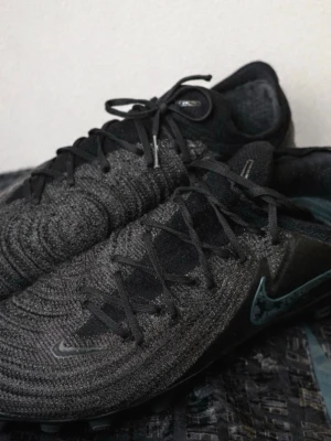 NIKE PHANTOM GX II ELITE AG-PRO SHADOW - SVART/GRÖN - Säljer ett par Nike Phantom fotbollsskor i svart färg med mörk gröna detaljer. Skorna är använda men i bra skick. Ovandelen är hel utan sprickor eller hål och ger bra bollkänsla. Sulorna har normalt slitage efter spel men dubbarna är hela och ger fortfarande bra grepp. Original Nike dustbag medföljer. Original pris strax under 2900kr