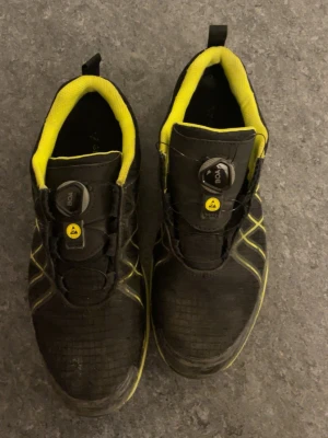 Svarta sneakers med BOA-spänne från Gesto - Svarta sneakers från Gesto med gula detaljer och innersula. Skorna har BOA-spänne för enkel justering och sitter riktigt skönt på foten. Vattentäta och med slitstark sula, perfekta för dig som vill ha både funktion och stil. Materialet är syntet och textil.