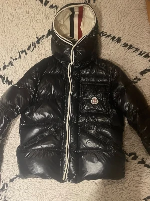 Moncler jacka - PRISSÄNKNING - ORDP. 3299 NU 2799! Säljer en stilren och klassisk Moncler”Branson” i svart med vita detaljer. Jackan är i storlek 3 (motsvarar Medium). Det finns två små fläckar (se bild), inget som påverkar funktion eller helhetsintryck.  ✔️ Varm och bekväm ✔️ Blank finish, ikonisk Moncler-design ✔️ Original patch på bröstet ✔️ Dragkedjor och knappar i bra skick  Perfekt vinterjacka som funkar både till vardag och mer uppklätt. Hör av dig vid frågor, så svarar jag!