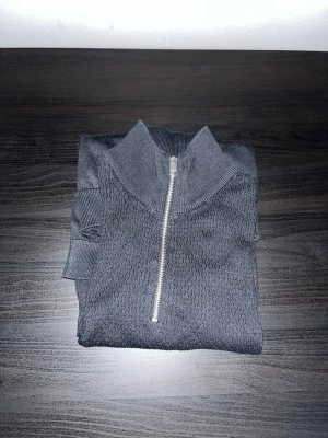 Svart stickad half zip från Jack & Jones - Säljer en svart stickad tröja från Jack & Jones med half zip och hög krage. Tröjan har ribbade muddar vid ärmslut och nederkant samt en snygg strukturstickad ovandel. Perfekt för lager på lager under höst och vinter. Knappt använd!