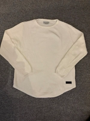 Vit långärmad tröja Just Junkies - Säljer en vit långärmad tröja från Just Junkies i storlek M. Tröjan har en strukturerad, ribbad yta och rund hals. Perfekt för lager på lager och enkel att matcha med olika outfits. Diskret logopatch nertill.