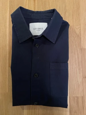 Mörkblå overshirt från Les Deux - Jättesnygg mörkblå overshirt från Les Deux. Overshirten är i jättebra skick och har inga skador.  Nypris ca 800 kr mitt pris endast 349 kr. Fraktar inom 1 dag, om du har någon fundering så är det bara att höra av sig😊