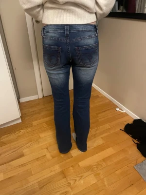 Blå bootcut jeans med broderade fickor - Säljer ett par lågmidjade jeans ifrån Gina tricot. Dom är mörkblå med röda detaljer. Säljer för 200. Knappt använda. 