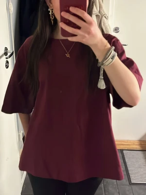 Vinröd oversized tshirt - Säljer en vinröd t-shirt med loose passform och korta, vida ärmar. Toppen har en enkel, stilren design. Storlek S