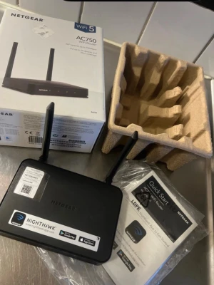Netgear AC750 WiFi Router (R6020) - Netgear AC750 WiFi Router med dubbla antenner, stöd för WiFi 5 och hastigheter upp till 750 Mbps. Passar upp till 10 enheter och har bred täckning. Inkluderar originalkartong, manual och emballage. Produkten ser ut att vara i gott skick utan synliga defekter.