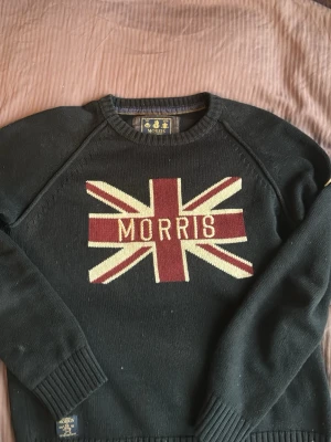 Mörkblå stickad tröja Morris S - Snygg mörkblå stickad tröja från Morris. Inga defekter. Har en logga på vänster armen. Passar längden 165-180. Den sitter slim på kroppen
