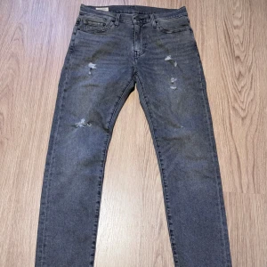 Levi's 512 grå slim jeans W30 L32 - Snygga grå Levi's 512 jeans med slim fit och slitna detaljer på benen. Klassisk femficksmodell med dragkedjegylf och läderpatch bak. Perfekta för dig som gillar en smalare siluett och streetkänsla.
