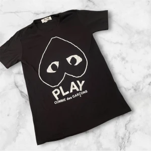 Svart Comme des Garçons Play t-shirt - Svart t-shirt från Comme des Garçons Play med stort vitt hjärta med ögon och logotyp på bröstet. Klassisk rund hals och korta ärmar. Tillverkad i mjuk bomull för en skön känsla och stilren look.