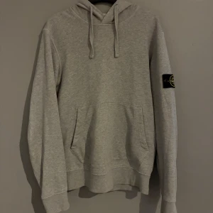 Grå hoodie från Stone Island - Grå hoodie från Stone Island med klassisk logotyp-patch på vänster ärm.