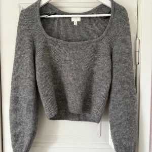 Grå ribbstickad tröja H&M - Mysig grå ribbstickad tröja från H&M med bred, fyrkantig ringning och långa ärmar. Tröjan är klassisk med en enkel design som passar perfekt till jeans eller kjol. Perfekt för lager-på-lager under kyliga dagar.