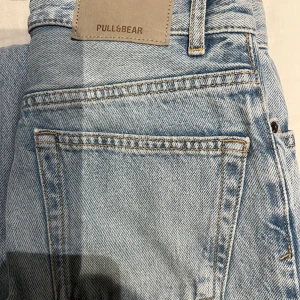 Ljusblå raka jeans från Pull&Bear - Ljusblå jeans från Pull&Bear med hög midja och raka ben. Klassisk femficksmodell i denim med råa, fransiga benslut och snygga detaljer i silvermetall. Perfekta för en avslappnad och trendig look. Jenssen är helt nya!