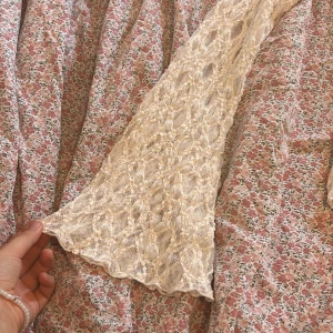 Vit spetsblus från Gina Tricot - Superfin vit blus från Gina Tricot i storlek S. Blusen har långärmade spetsärmar och ett vackert spetsmönster över hela plagget. Rundad halsringning och figurnära passform. Perfekt för dig som gillar romantisk och feminin stil.