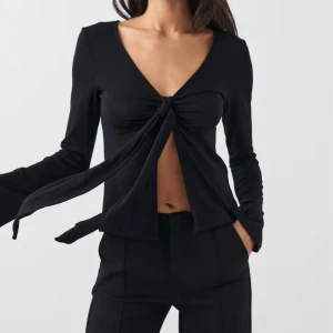 tie front long sleeve top Gina  - Svart långärmad topp från Gina Tricot. Toppen har v-ringning och en snygg knytning framtill. Ärmarna är långa och lätt utsvängda. Skriv om du undrar något🫶🏼