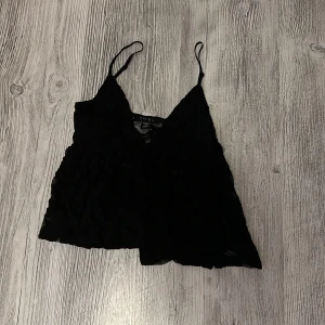 Svart  linnetopp  - Säljer en svart linnetopp från newyorker i storlek XXS. Toppen har tunna axelband, v-ringning och är gjord i ett genombrutet spetsmaterial som ger en romantisk vibe. Perfekt att styla med jeans eller kjol för en trendig look. Den är helt ny, aldrig använd bara testad.