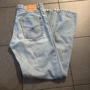 Levi's 501 ljusblå jeans W28 L34 - Klassiska Levi's 501 jeans i ljusblå denim med raka ben och knappgylf. Byxorna har fem fickor, ikonisk läderpatch bak och den röda Levi's-taggen på bakfickan. Perfekt vintagekänsla och tidlös stil. Uppsydda till 32 längd.