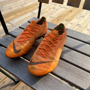 Nike Mercurial Vapor 360 orange fotbollsskor - Säljer ett par Nike Mercurial fotbollsskor i en riktigt snygg orange färg med svarta detaljer och snörning. Perfekta för dig som vill sticka ut på fotbollsplanen.