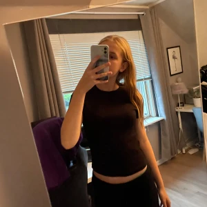 Svart ribbad t-shirt från H&M - Svart ribbad t-shirt från H&M med rund halsringning och korta ärmar. Säljer då den blivit för liten, enkel att matcha med och göra outfits. Storlek 170 men känns lite mindre då den är tajt och lite crop top