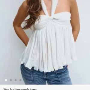 Vit plisserad halterneck topp - Säljer en vit halterneck topp med plisserat tyg och snygg knytning i nacken. Toppen har en flowy och luftig passform med breda band och lätt ribbad struktur. Köpt begagnad men helt ny utan prislapp. Säljer pga för liten storlek. Den är i S men skulle mer säga XS 