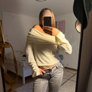 Offshoulder ljusgul stickad tröja - Superfin offshoulder tröja i ljusgul färg med långa ärmar och lätt croppad passform. Tröjan är stickad och har en snygg omlott-detalj över axlarna som ger en chill men ändå trendig vibe. Perfekt att styla med jeans eller kjol för en cool look.