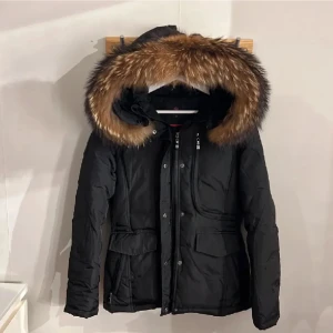 Svart dunjacka med pälsluva - Snygg svart dunjacka med en stor fluffig päls runt luvan som är på och avtagbar.  Jackan har dragkedja och knappar framtill, två stora fickor med lock och en skön, varm känsla. Perfekt nu inför de kalla dagar.  Storlek 36, men passat mig som vanligtvis bär storlek 38. Nypris 4999kr från Miinto. Pris kan diskuteras.