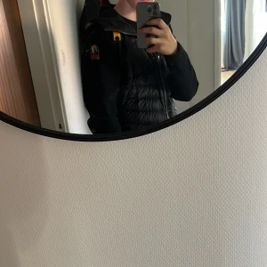 Svart dunväst från Parajumpers - Säljer en svart dunväst från Parajumpers med huva och snygga quiltade partier. Västen har dragkedja framtill, klassisk PJS-logga på axeln och detaljer i gult. Perfekt för lager-på-lager och riktigt street. Materialet är polyester och dun. Storlek xs. Lägg gärna ett bud