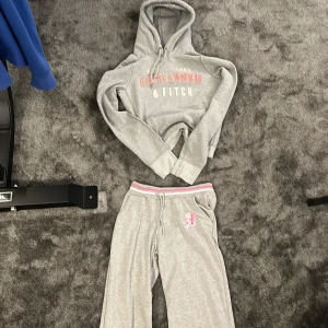 Grå mjukisbyxor + Hoodie Abercrombie & Fitch M - Ett set från från Abercrombie & Fitch - HOODIE + MJUKISBYXOR, går att köpa BÅDA ELLER ETT PLAT VAR O EN, med rosa och vit rand i midjan och broderad rosa logga på ena benet. Byxorna har normal passform, raka ben och är tillverkade i mjukt bomullsmaterial. Perfekta för chill dagar eller när du vill vara extra bekväm. Hoodie + mjukisbyxor
