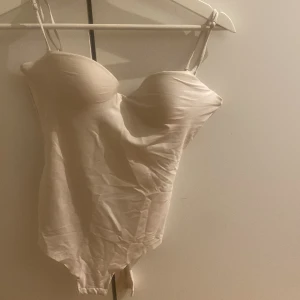 Body - Säljer denna populära vit/beiga body från hm i storlek 80B, passar på mig som har S vanligtvis. Bodyn är bara använd en gång
