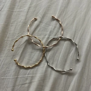  armband set i guld, silver & rosé - Säljer tre snygga  armband i metall – ett i guld, ett i silver och ett i roséguld. De har öppen design med små kulor i ändarna och en cool, vriden form som ger en modern vibe. Perfekta att mixa och matcha för en personlig stil.