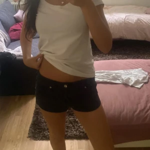 Svarta lågmidjade shorts - Säljer ett par svarta shorts med låg midja och klassisk femficksdesign. De är korta och har en slim passform som sitter snyggt på kroppen. Perfekta för varma sommardagar och enkla att matcha med din favorit-topp.