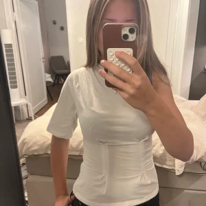 Vit oneshoulder topp. Står att den är xxs men den passar på mig som har s/sx - Säljer en vit oneshoulder topp från Nelly i mjuk bomull. Toppen har en kort ärm på ena sidan och är ärmlös på andra, med figurnära passform och snygga sömdetaljer framtill. Perfekt för dig som vill sticka ut med en unik och trendig look.