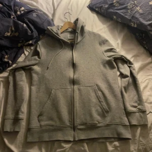 Grå Jack&Jones ziphoodie - Grå zip-hoodie från Jack & Jones. Nypris 550 och är använd ett fåtal gånger. Men inga defekter och passar perfekt på er som har storlek L. Hör av dig vid frågor😁