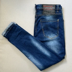 Dsquared2 blå jeans med original slitningar w31 - Snygga blå jeans från Dsquared2 med coola slitningar och tvättade detaljer. Klassisk femficksmodell med smal passform och låg midja. Jeans i bomull med en modern look, perfekt för dig som gillar streetstyle.