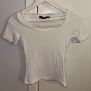 Vit croppad topp från Bik Bok - Säljer en enkel och fräsch vit topp från Bik Bok i storlek XS. Modellen är croppad med rundad halsringning och korta ärmar. Materialet är mjuk bomull som känns skönt.