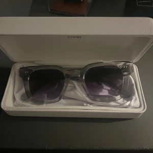 Chimi glasögon grey 04 - Snygga solglasögon från CHIMI med transparent grå båge och fyrkantig form. Glasögonen är knappt använda och är i väldigt bra skick. Man får med sig allt man behöver som tvättduk och sånt (visas på bild). Nypris är 1450. Skriv om ni är intresserade, pris är inte hugget i sten