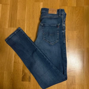 Blå slim jeans från Replay - Säljer ett par klassiska blå jeans från Replay med slim fit. Jeansen har fem fickor, snygga sömmar på bakfickorna och en läderpatch med Replay-logga bak i fickan. Ena framfickan har ett hål men syns inte