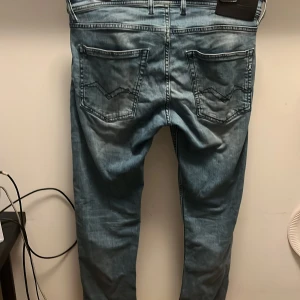 Replay Grover ljusblå jeans straight fit - Säljer ett par Replay Grover jeans i ljusblå tvätt med raka ben och klassiska fem fickor. Jeansen har snygga slitningar och detaljerade bakfickor. Modellen är straight fit och materialet är mjukt denim för en skön känsla.